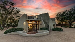 A modern house with a unique architectural design, featuring a large entrance and a staircase leading to an upper level. - Eclectic Santa Fe Ranch Home + Casita with Hot Tub in Cave Creek (Cave Creek)