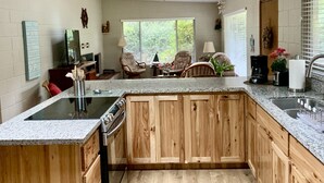 A kitchen with wooden cabinets, a granite countertop, a built-in stove, and a dining area with two chairs and a table.