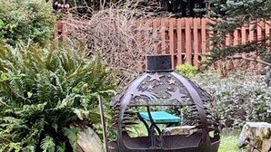 A garden with a decorative metal sculpture, a wooden fence, and various plants.