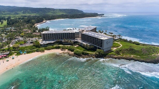 Ein modernes Hotel mit großer Glasfassade mit Blick auf Strand und Meer.