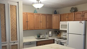 Eine Küche mit Holzschränken, einem weißen Kühlschrank, einer Mikrowelle und einem Essbereich mit Hockstühlen.