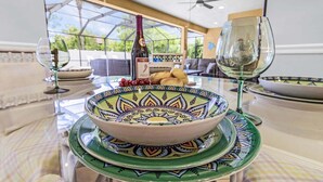 Une table à manger ornée d’un saladier décoratif, d’une bouteille et d’un verre.