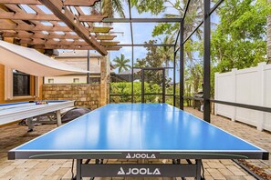 An outdoor ping pong table with a wooden pergola overhead. - Outdoor Pool Table and Ping Pong Table, Heated Pool - Villa Terrapin - Roelens Vacations (Cape Coral)