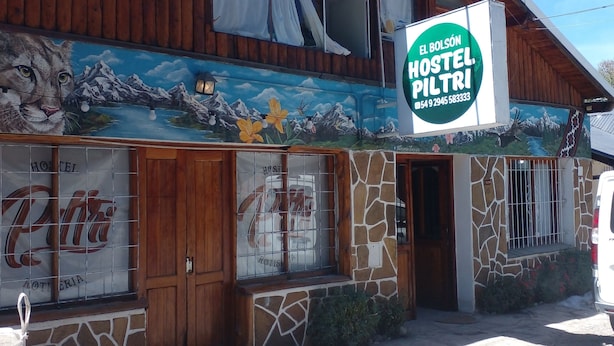 A hostel with a mural of a mountain landscape and a sign reading "El Bolson Hostel Piltri". - Hostel Piltri  (El Bolson)