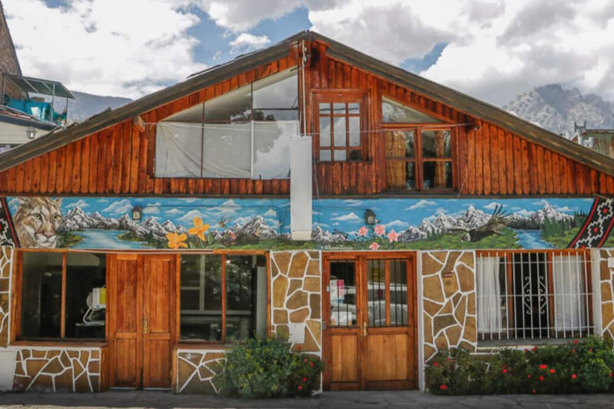 A rustic wooden house with a mural depicting mountains and wildlife.