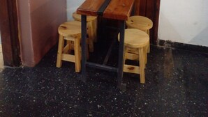 A small room with a wooden table and four stools, a door with a sign, and various wall decorations. - Hostel Piltri  (El Bolson)