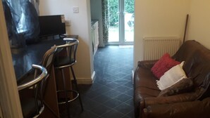 Un soggiorno con un divano in pelle marrone, un cuscino rosso e un angolo bar con sgabelli.