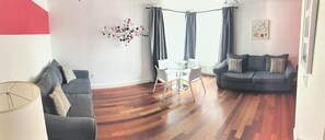Relax in this stylish living room with a sofa, armchair, and dining table for four.