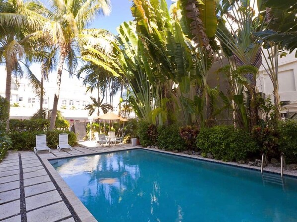 Relax by the serene pool surrounded by lush tropical vegetation and lounge under a shaded canopy.