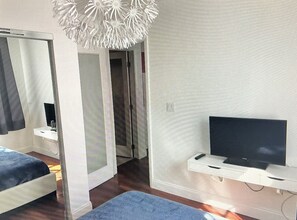 Relax in a stylish space with a large mirror, flat-screen TV, and unique ceiling light fixture.