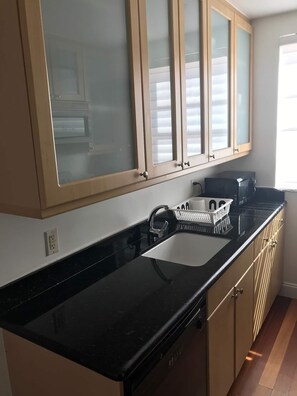 Enjoy cooking in this well-equipped kitchen with a sleek countertop, beige cabinetry, and a coffee maker.