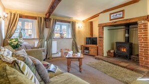 A cozy living room with a fireplace, comfortable seating, and a television. - Church Cottage (CA), Castle Acre, Norfolk (Castle Acre)