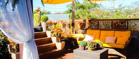 An outdoor patio with wicker furniture, potted plants, and a yellow umbrella.