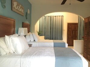 Habitación de hotel con dos camas, cabecero de madera, un reloj de pared y un cartel que dice 'Relax'.