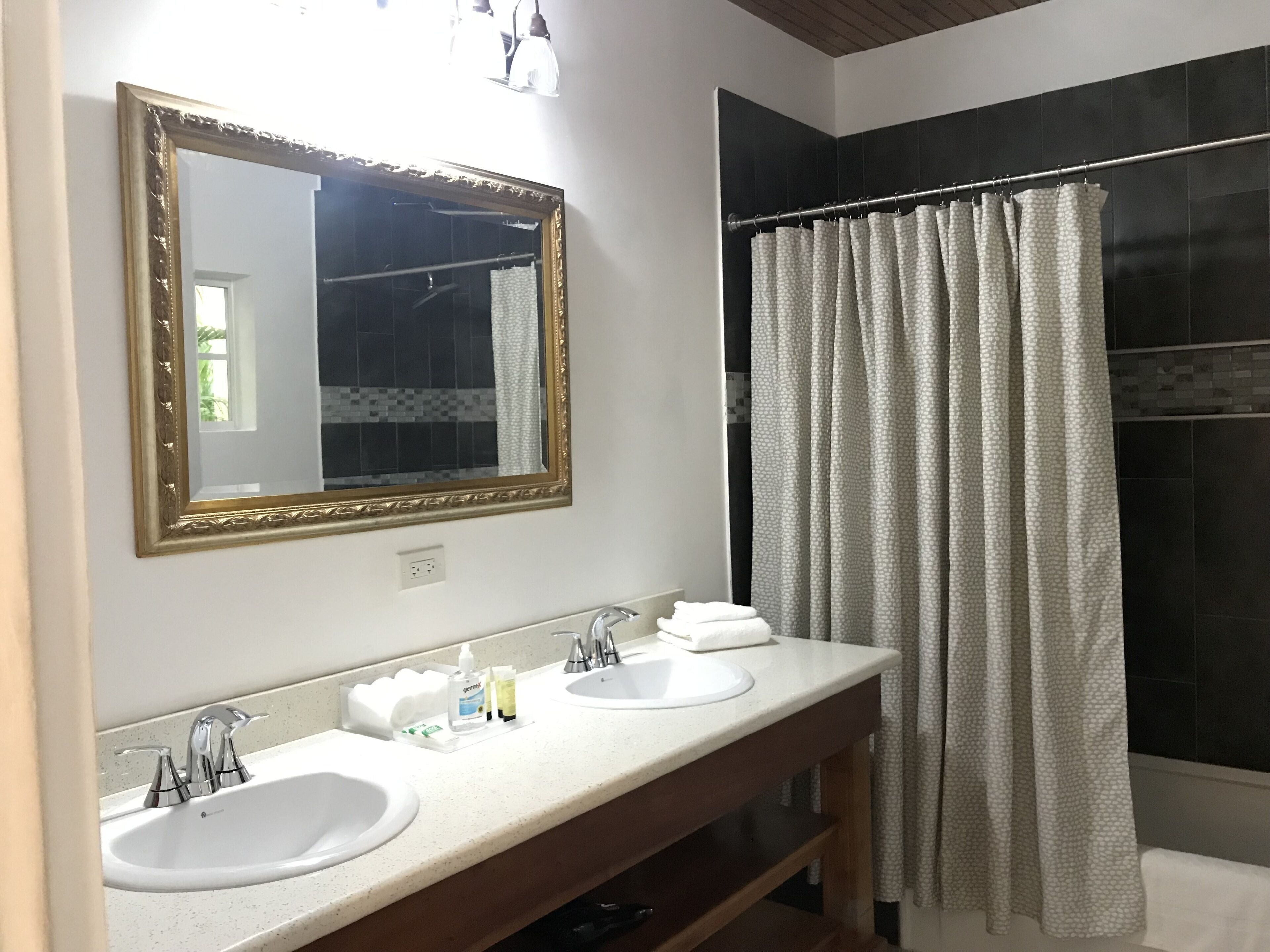 A bathroom with two sinks, a mirror, and a shower curtain.