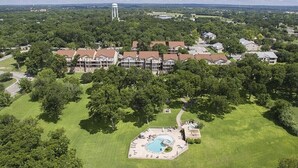 Vista aérea de un hotel con varias edificaciones, un amplio césped y una piscina.