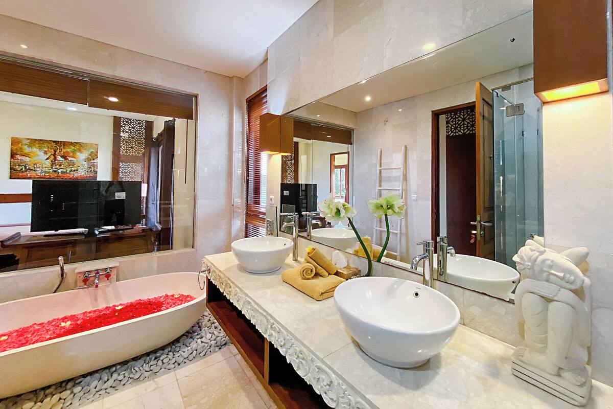 A modern bathroom with a large bathtub, two sinks, and a shower.