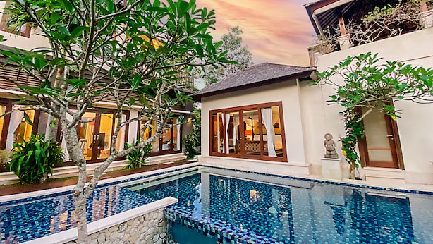 A pool with mosaic tiles, a stone wall, and a building with large windows and a balcony. - Alea Villa (Ungasan)