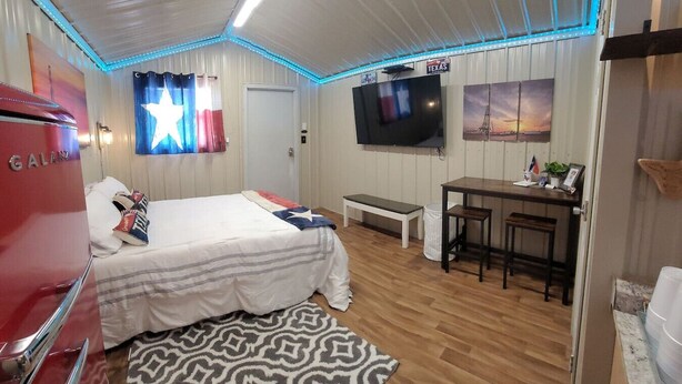 A hotel room with a bed, a desk, a television, and a red appliance. - City limits, off interstate I20 & west co rd WIFI (Odessa)