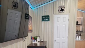 A compact room with a bed, a desk, a chair, and a bench. There are signs on the wall indicating city limits and a state emblem. - City limits, off interstate I20 & west co rd WIFI (Odessa)