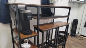 Una cafetera sobre una estantería de madera con estructura metálica negra.