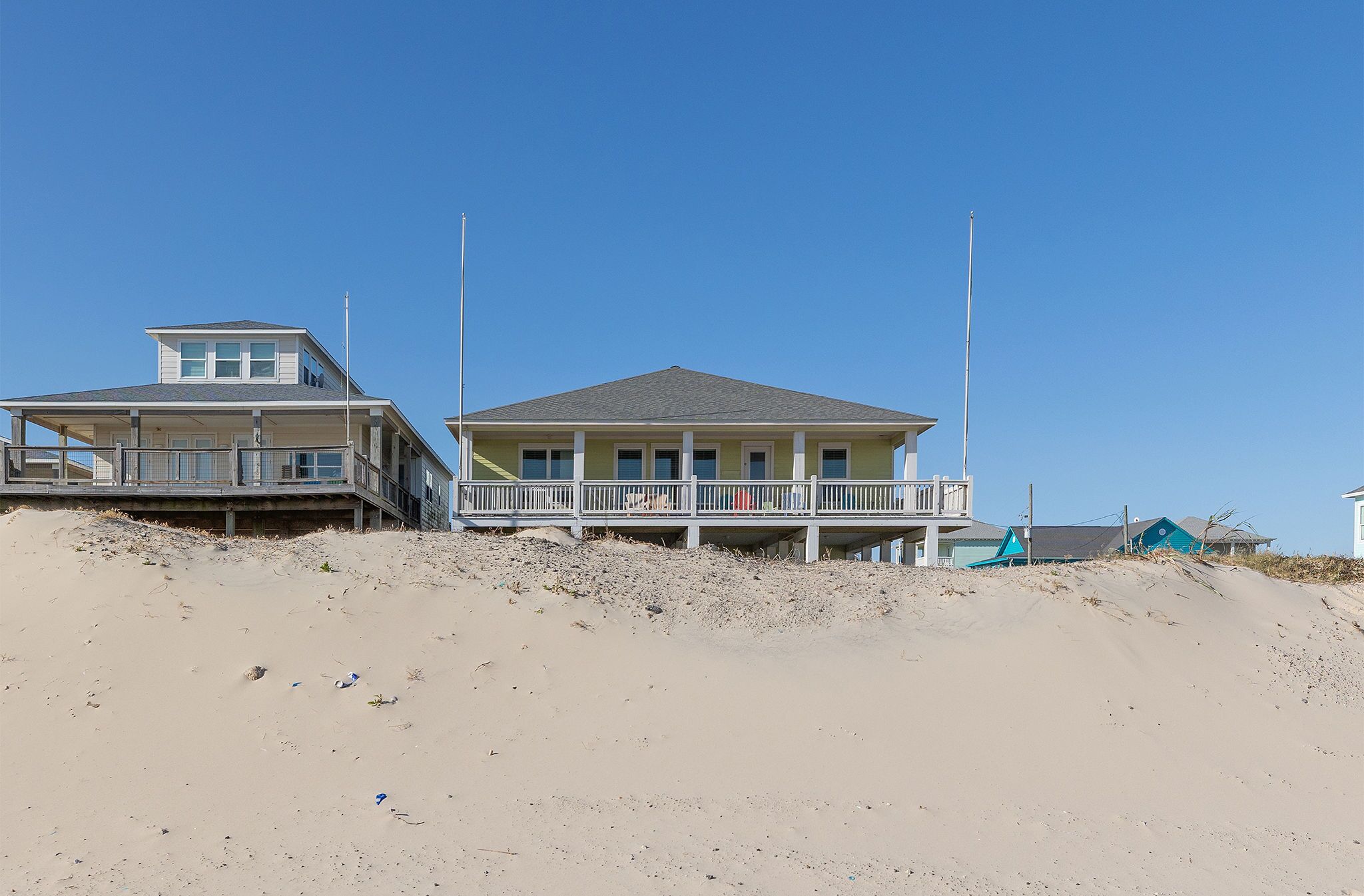 A beachfront house with a balcony and a second floor.