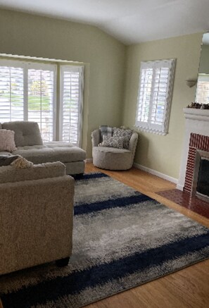 Cozy living room with a fireplace, armchairs, and ottoman.