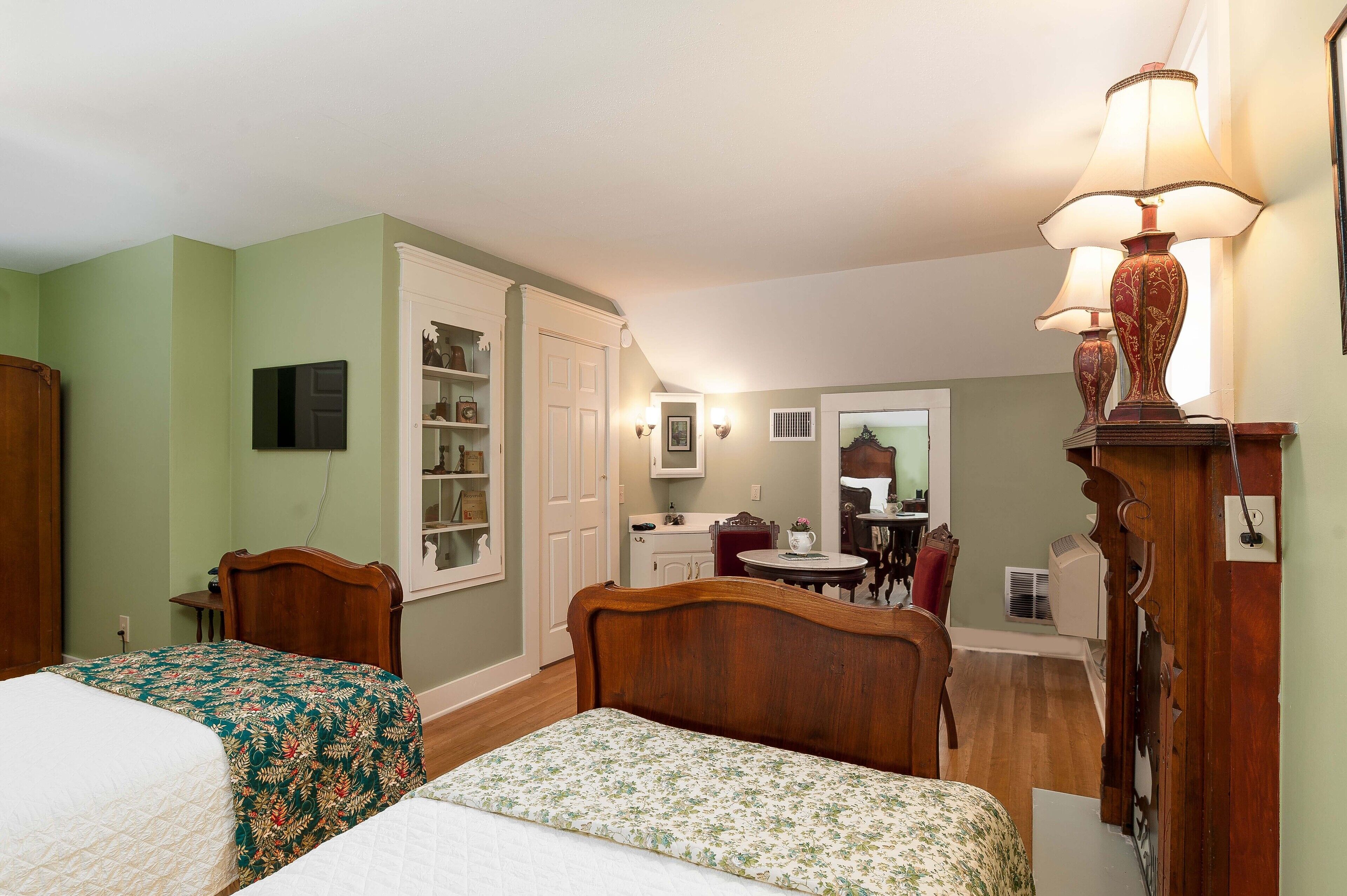 Une chambre avec deux lits, une tête de lit en bois, une table de chevet, une commode et un miroir.