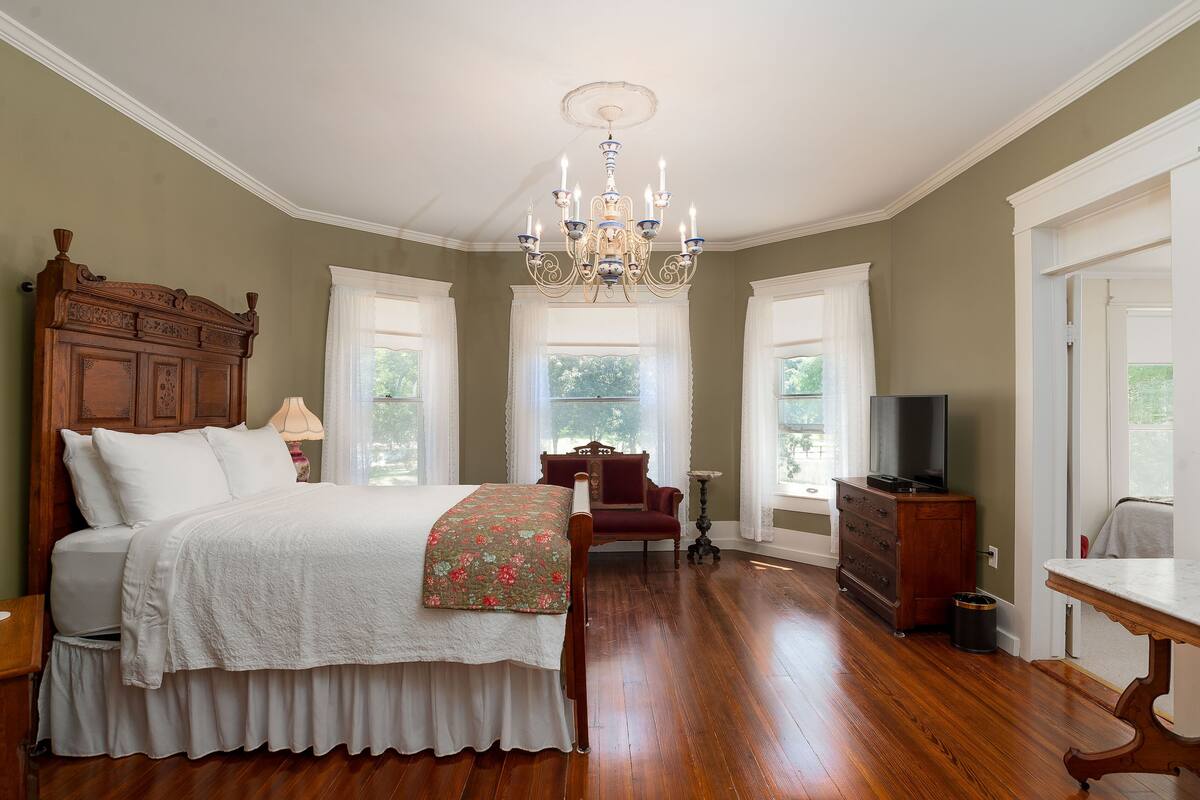 Une chambre à coucher avec un lit en bois, un lustre, une commode et un téléviseur.