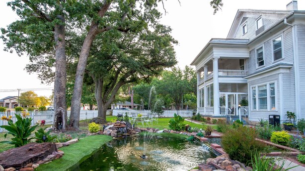 A residential property with a pond, a white fence, and a large house with a porch. - Oaklea Mansion Bed and Breakfast (Winnsboro)