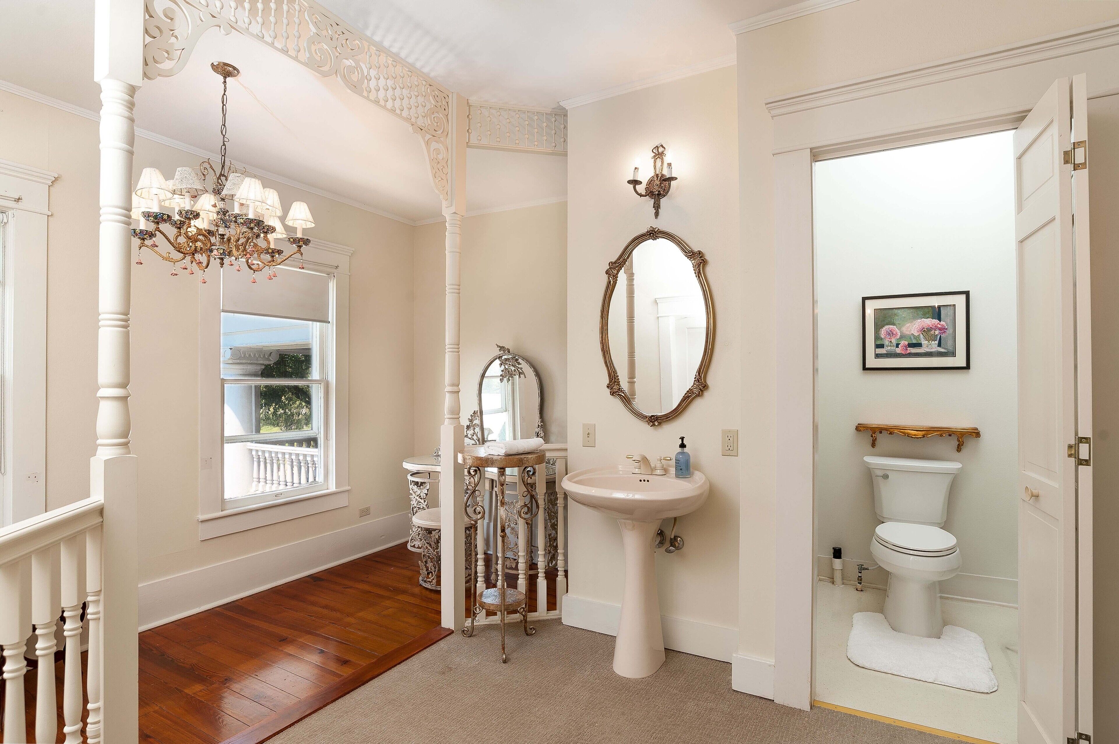 A bathroom with a pedestal sink, a freestanding mirror, and a chandelier.