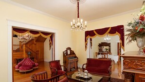 A formal dining room with a chandelier, red upholstered chairs, a wooden dining table, and a staircase leading to another room. - Oaklea Mansion Bed and Breakfast (Winnsboro)