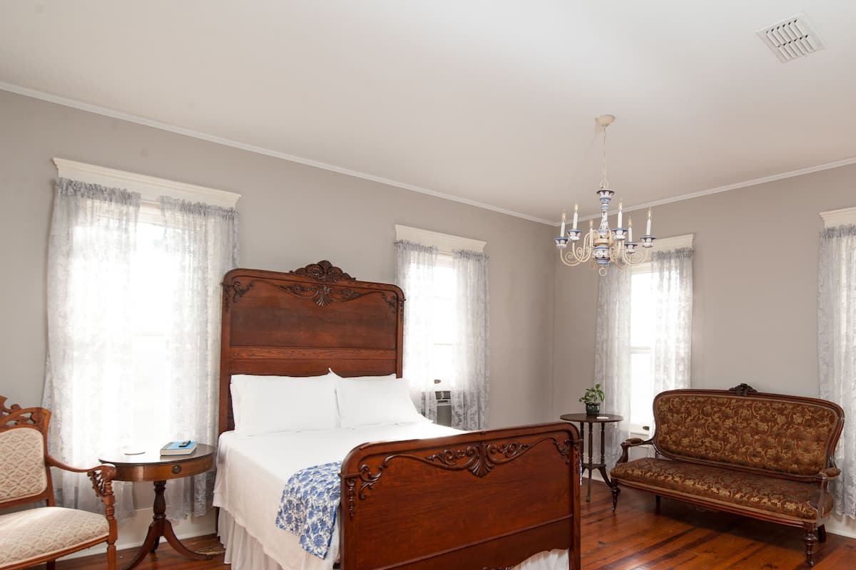 Une chambre à coucher avec un lit à baldaquin en bois, un canapé en bois, une petite table ronde et une chaise.
