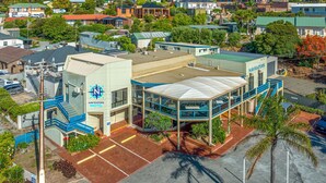 A hotel with a prominent sign, a covered outdoor area, and a parking lot. - Navigators Motel (Port Lincoln)