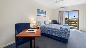 A hotel room with a bed, a desk, a chair, a ceiling fan, and a large window with a view. - Navigators Motel (Port Lincoln)