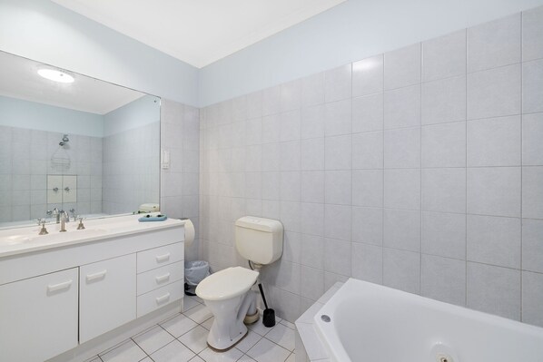 Un baño moderno con lavamanos, inodoro y bañera blancos.