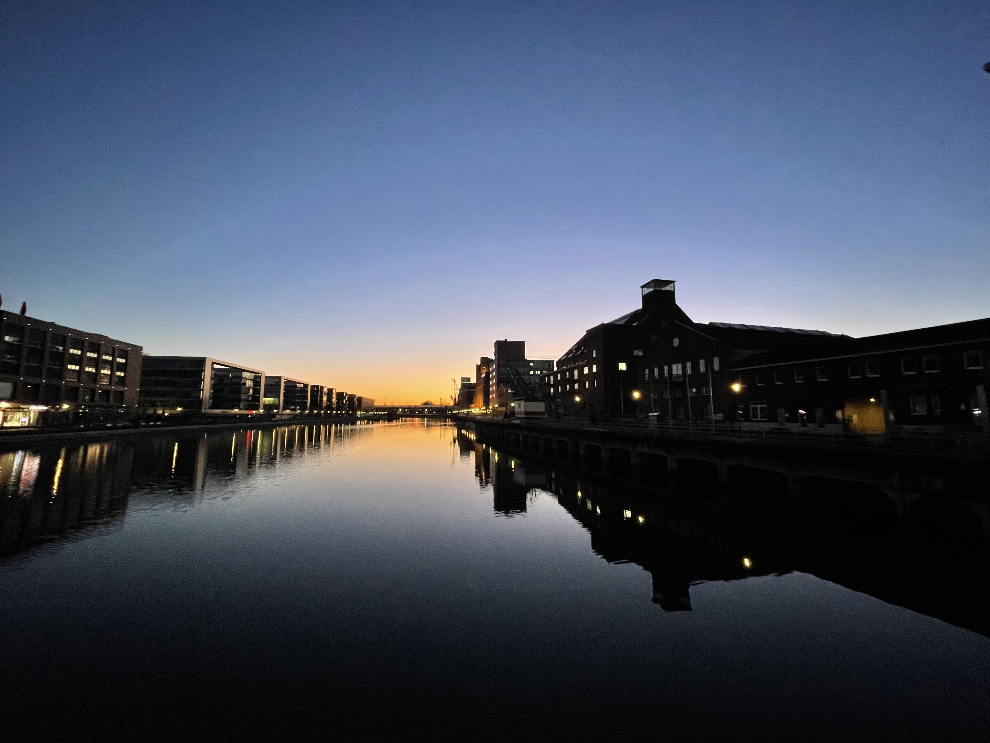Een rustige rivier die gebouwen weerspiegelt in de schemering.