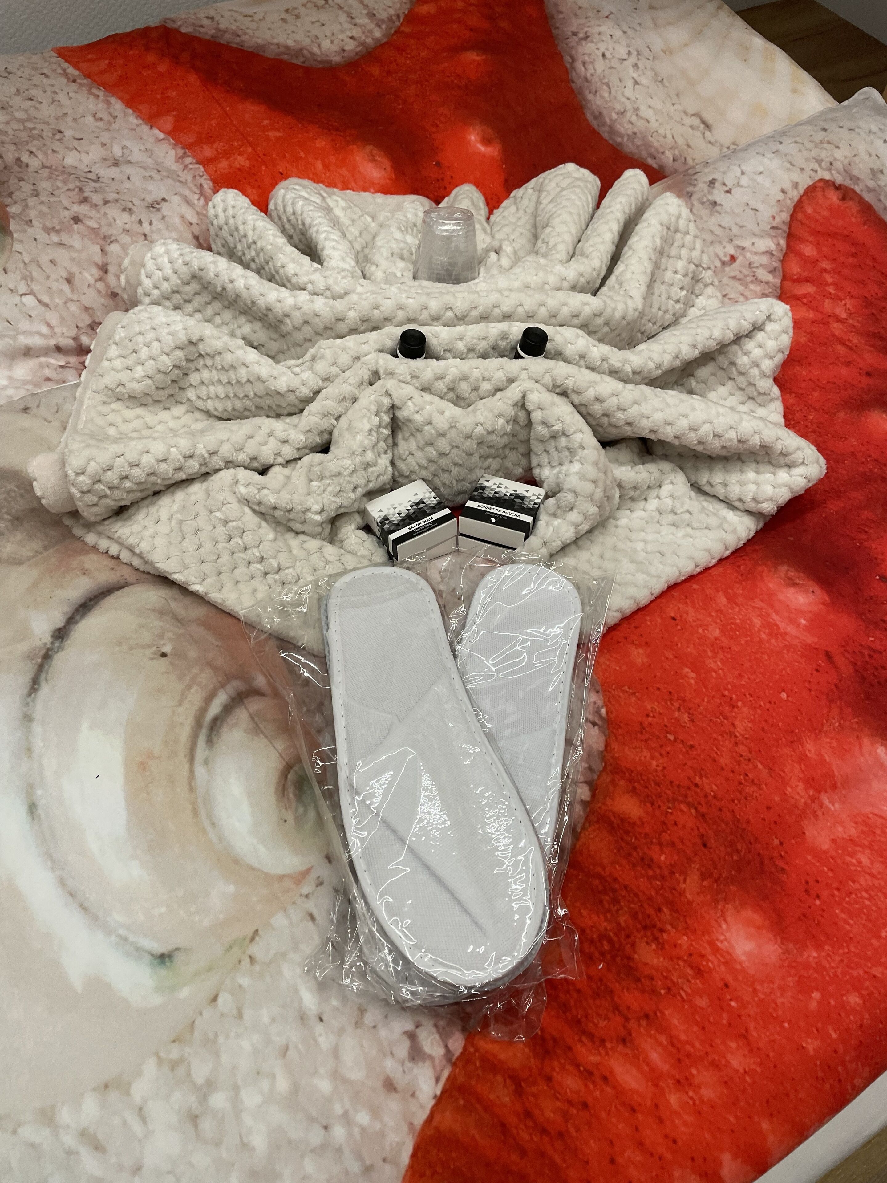 Un jouet en peluche, une paire de chaussons et une petite boîte dont la surface est ornée d’un motif et sur laquelle est inscrit un texte.