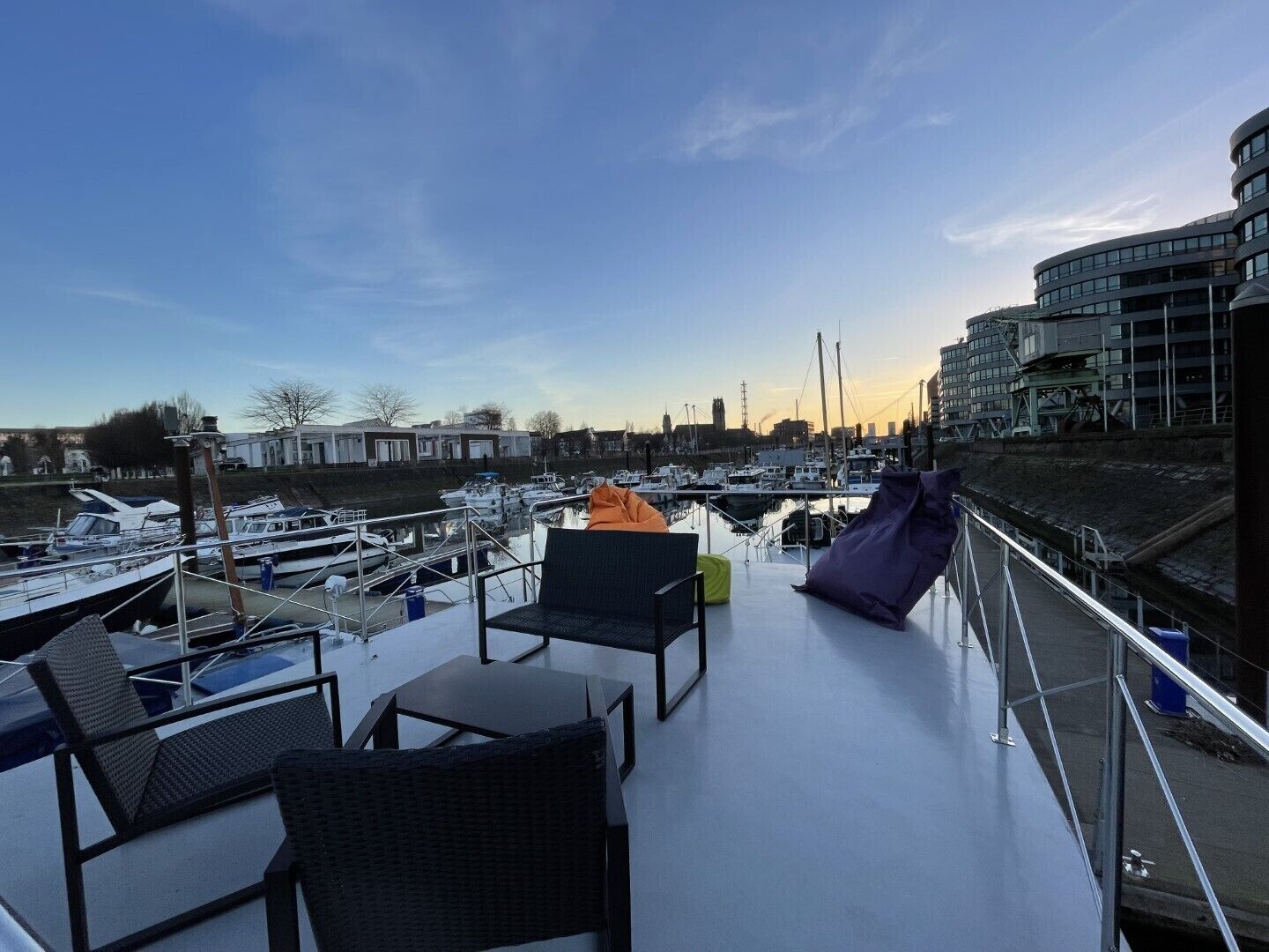 Une terrasse sur le toit, dotée d’un espace extérieur aménagé, offrant une vue sur une marina avec des bateaux et sur le panorama de la ville.