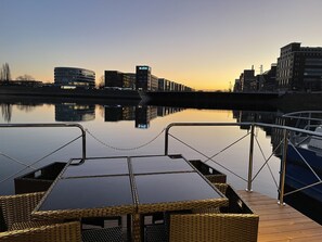 A calm waterfront view with a dock and a cityscape in the background. - Hausboot Lore (Duisburg)