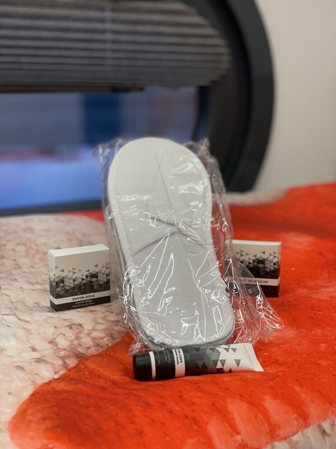 A pair of shoes wrapped in plastic, a box labeled 'SAVON DOUX Gentle Soap', and a smaller box with a geometric design.
