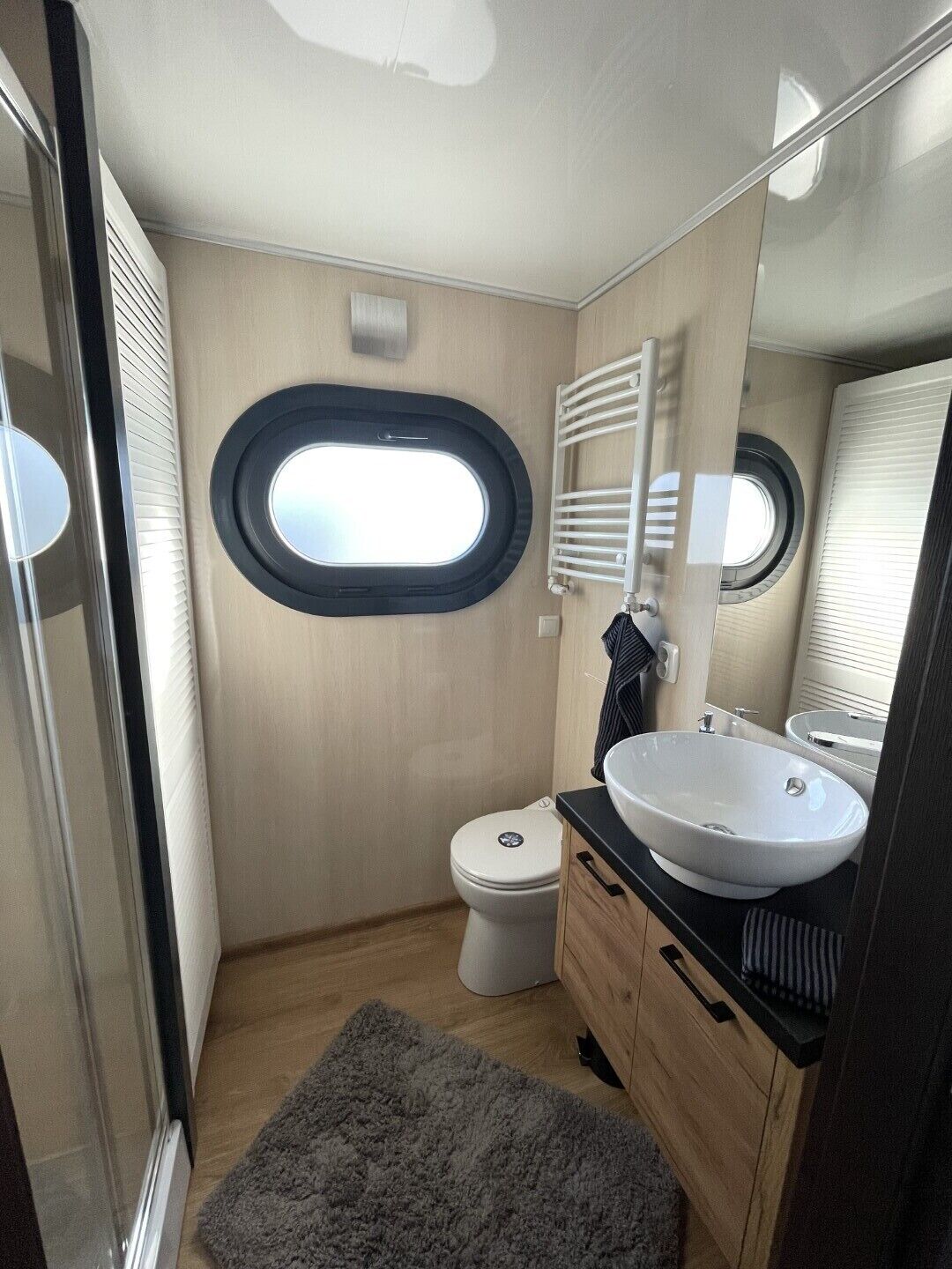 Ein kleines Badezimmer mit Toilette, Waschbecken, Spiegel und einem kleinen Fenster.
