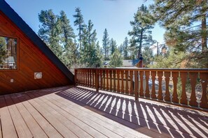 Un terrazza in legno con ringhiera, circondata da alberi.