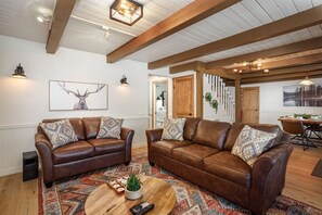 A living room with two leather sofas, a coffee table, and a painting of a deer on the wall.