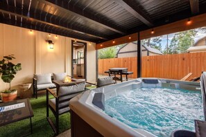 A backyard with a hot tub, outdoor seating, and a wooden deck.