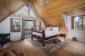 A high-ceilinged bedroom with a rustic wooden bed, large windows, and a view of the outdoors. - 🐻FamilyCabin🍿TheaterRoom🎱GameRoom🔋EVCharger 🐶PetFriendly (Big Bear)