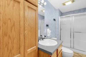 A modern bathroom with a wooden vanity, a white sink, and a glass shower enclosure. - Cardinals Perch (Campton)