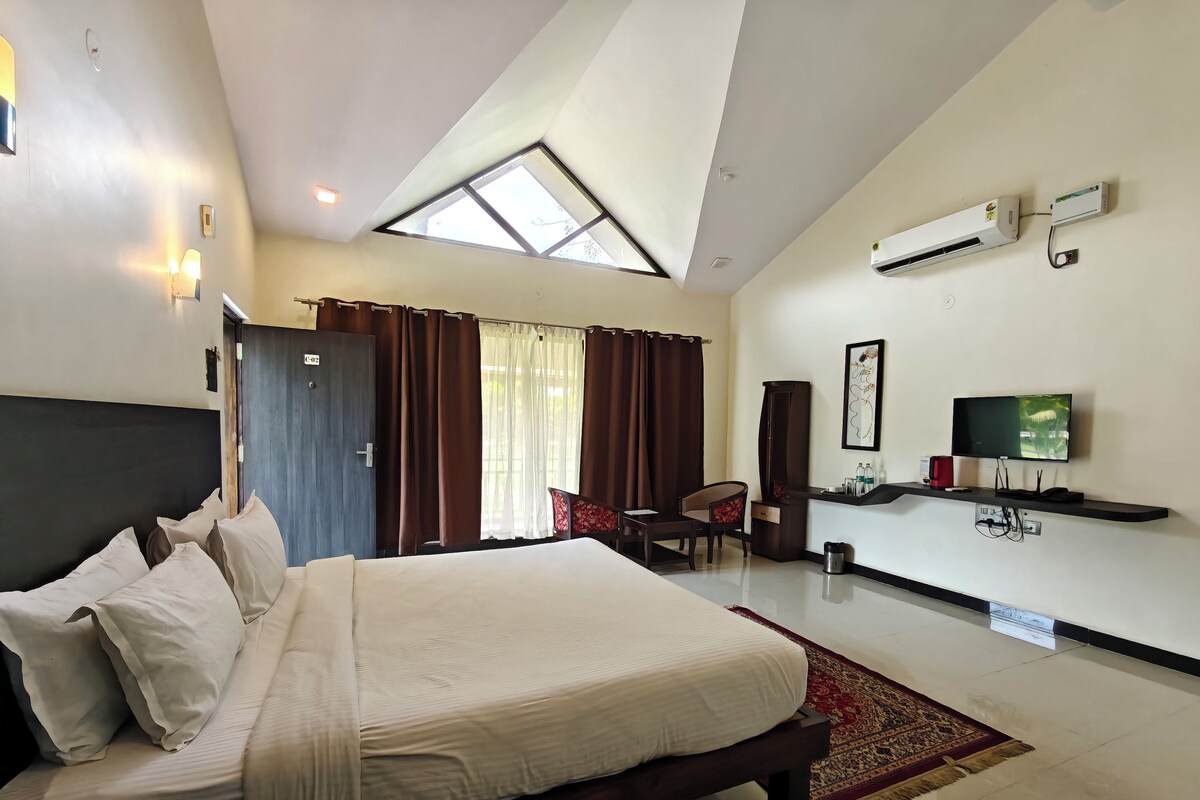 Quarto de hotel com uma cama, escrivaninha, cadeira, televisão e ar condicionado.