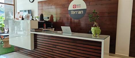 A reception desk with a sign reading 'MASTIFF SELECT Terrain,' a clock, and a laptop on the counter.
