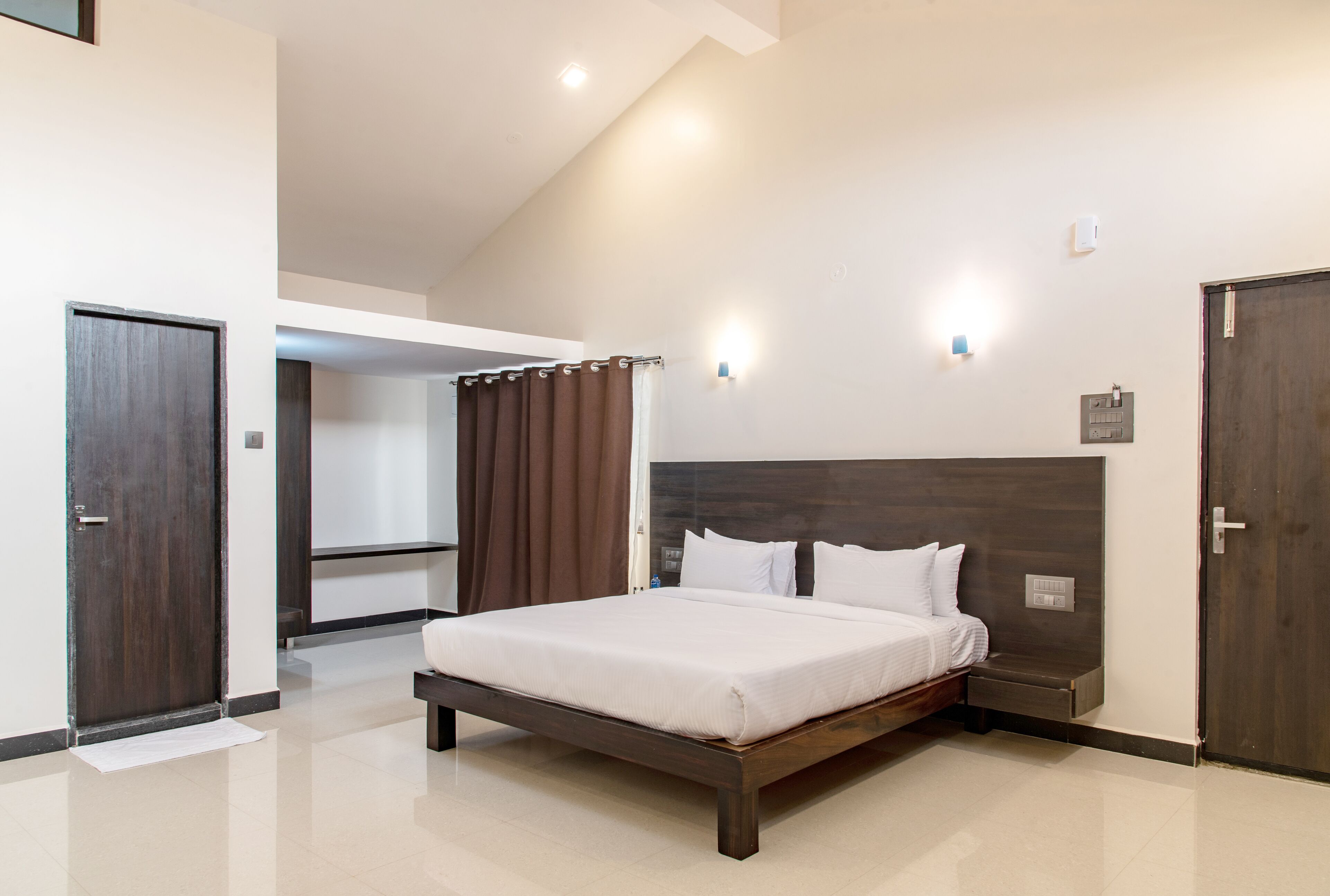 Ein modernes Schlafzimmer mit einem großen Bett, einem Holz-Kopfteil und einer Deckenleuchte.